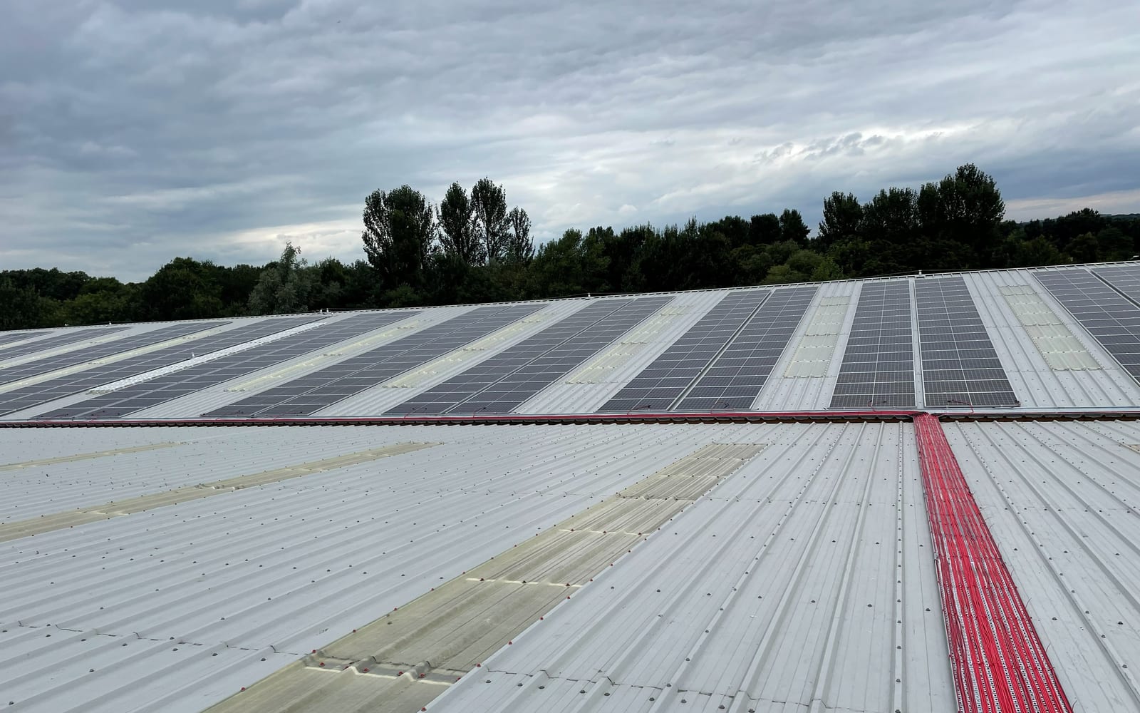 DC cable runs threading between the rooftop solar panel rows at Stiller