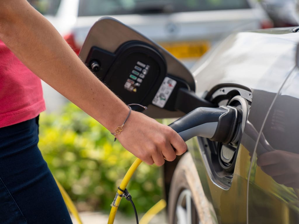 An electric car being plugged in to charge at a charge point
