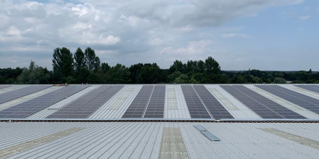 Rows of solar panels across the sheet-metal roof of the Stiller warehouse