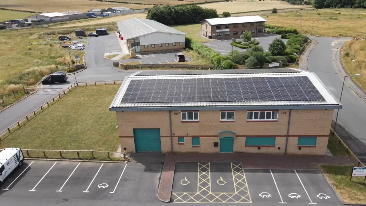 Aerial view of a brick commercial building with a rooftop solar array