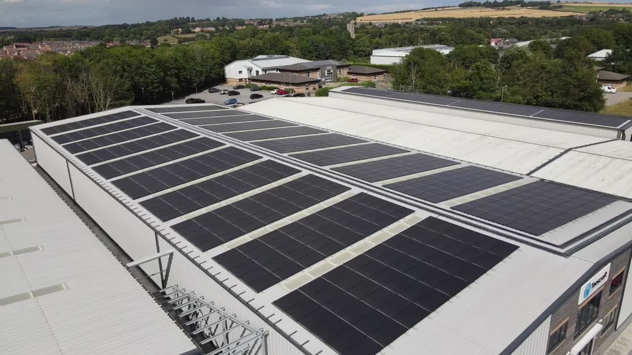 Aerial view of solar panels across a white-clad warehouse roof