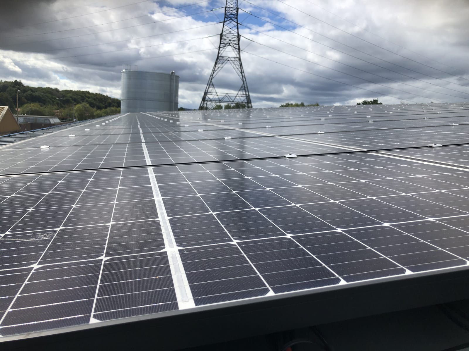 Commercial rooftop solar array with an electricity pylon in the background
