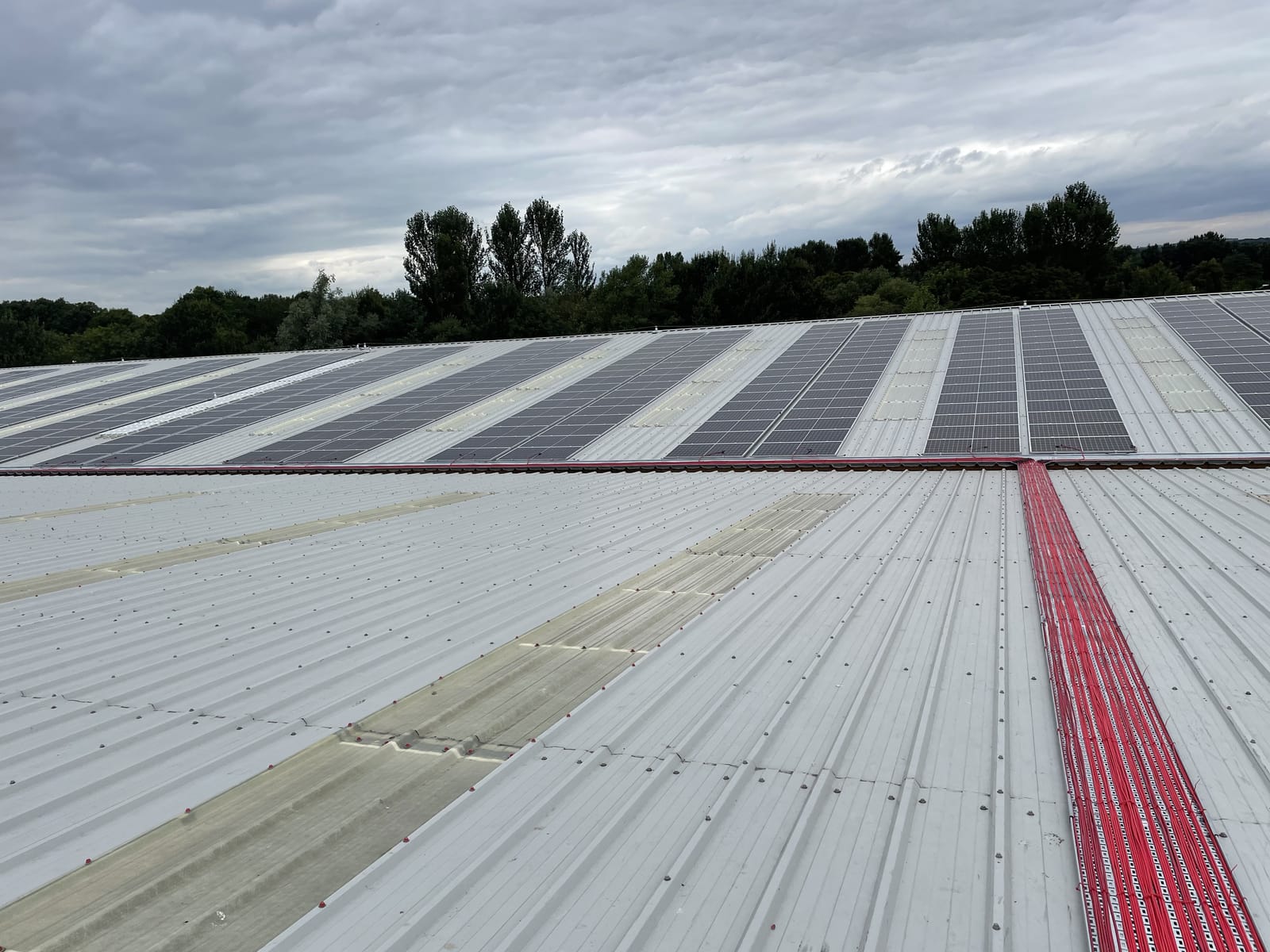 Solar panel array on a commercial sheet-metal roof, with a marked walkway between the rows
