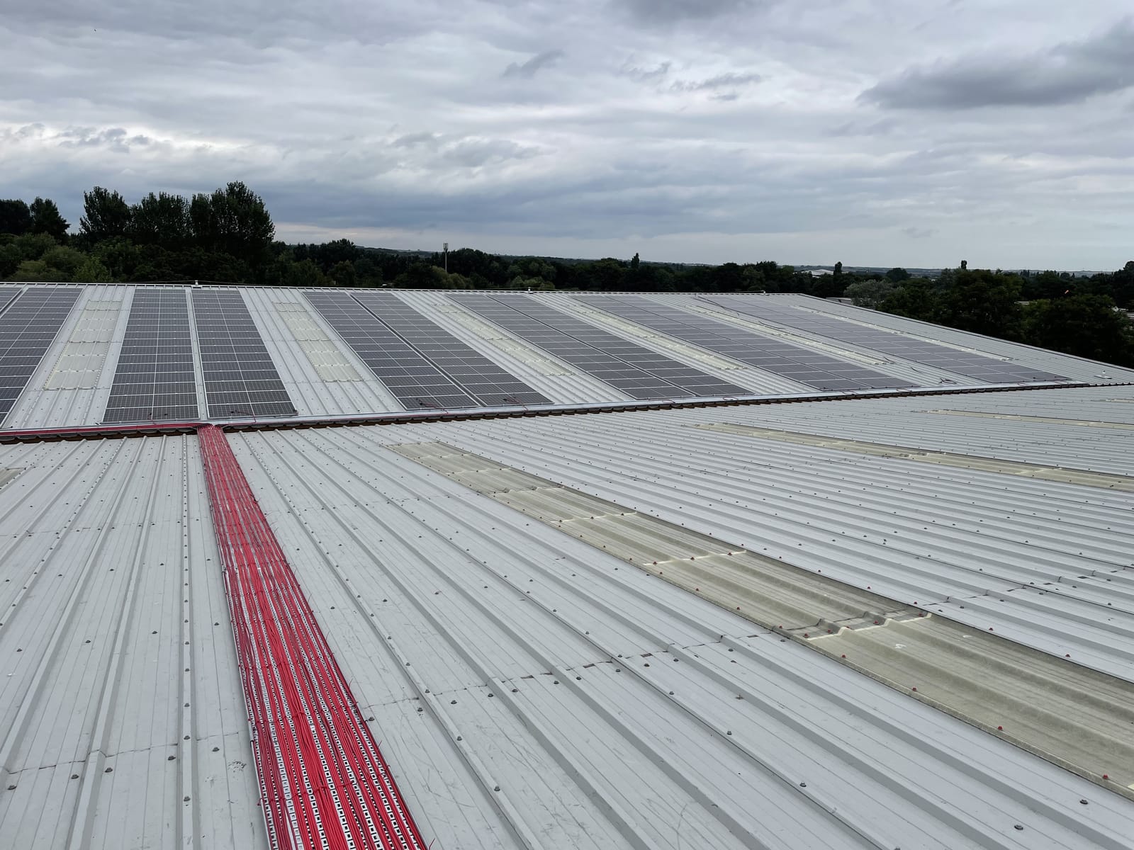 Solar panel array on a sheet-metal roof with a red safe-access walkway